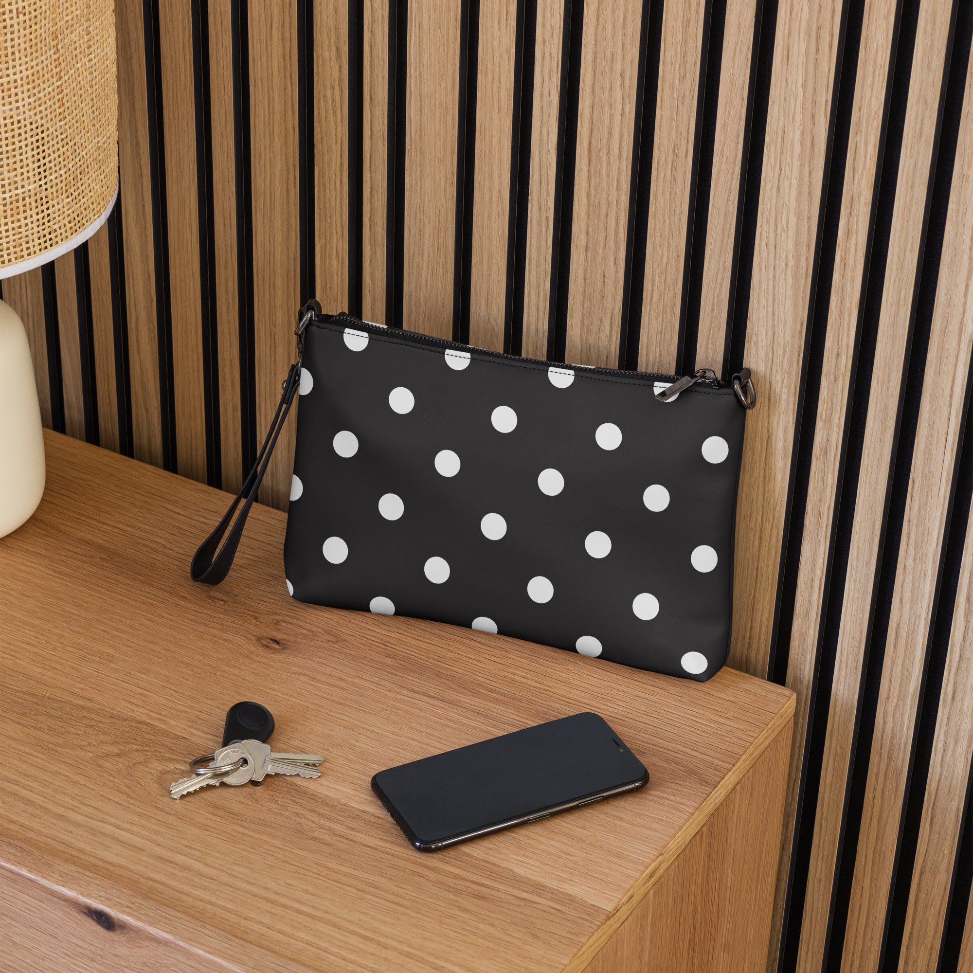 A black faux leather crossbody bag with white polka dots