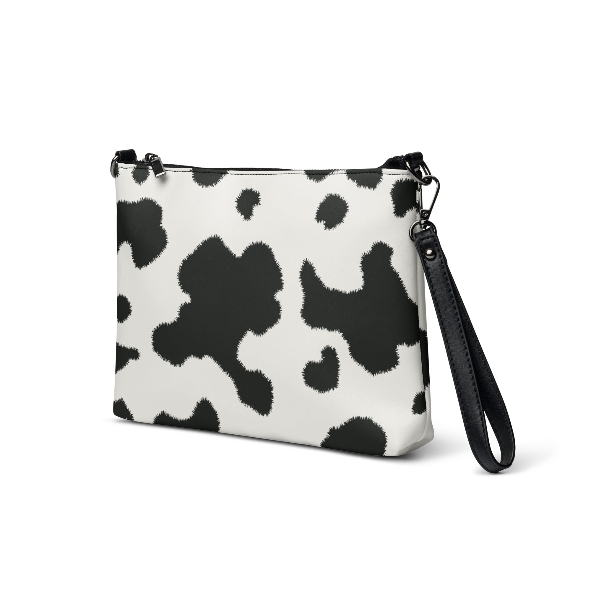 A faux leather crossbody bag with a cow print design, featuring a zip-top closure and an adjustable wrist strap.
