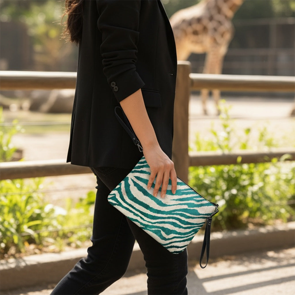 Person holding a green and white patterned clutch bag with a blurred background