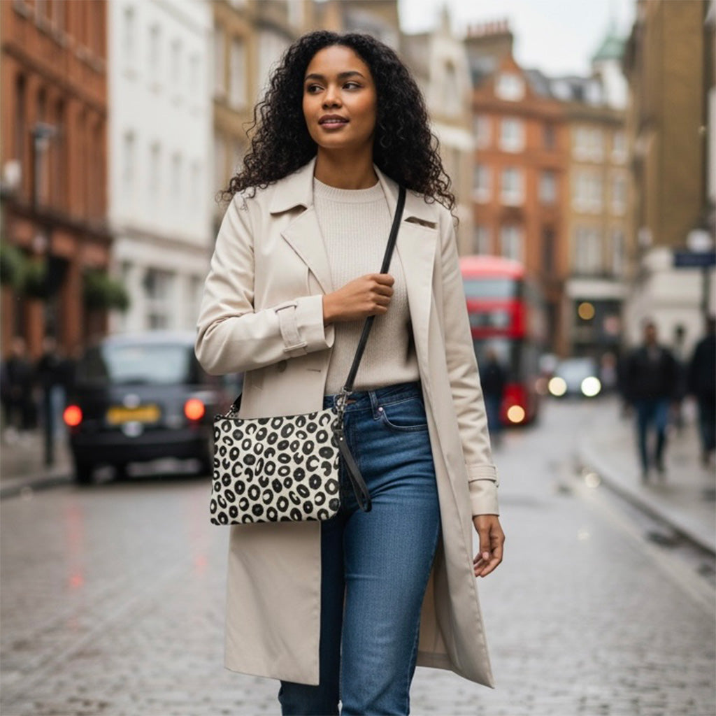 Woman in a beige coat with a leopard print bag walking on a city street.