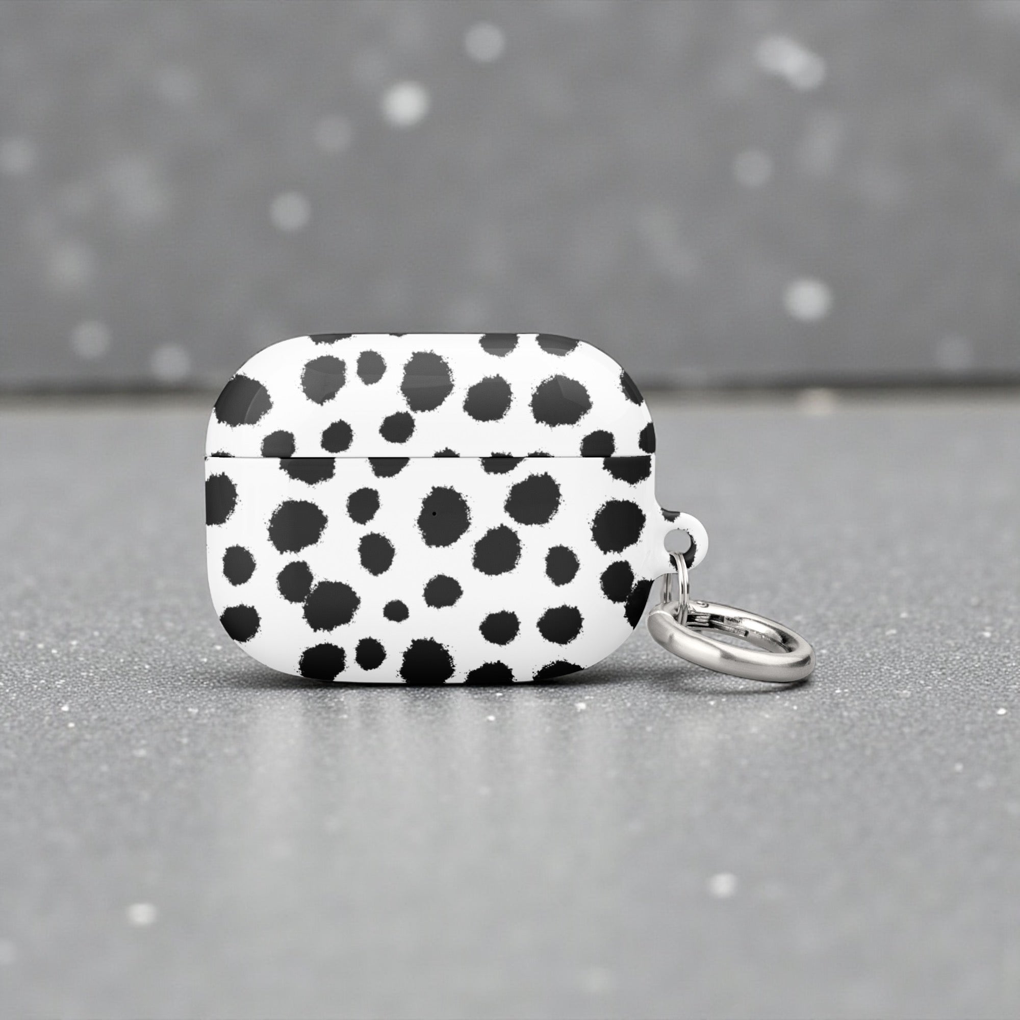 Black and white polka dot case with a keychain on a gray background