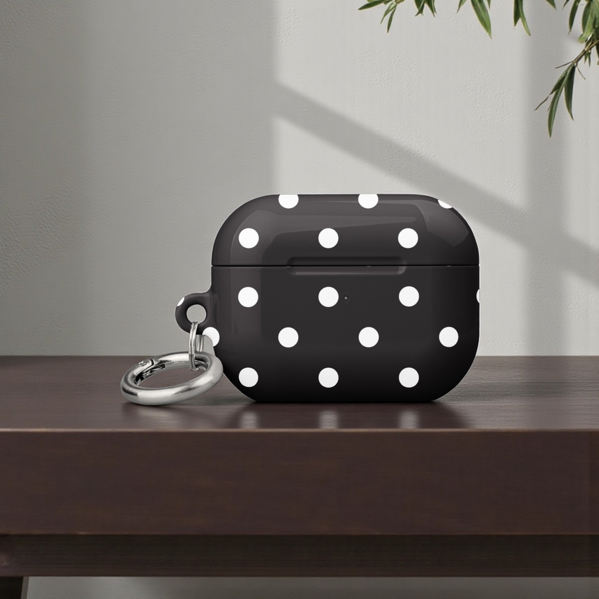 Black air pod case with white polka dots on a wooden surface