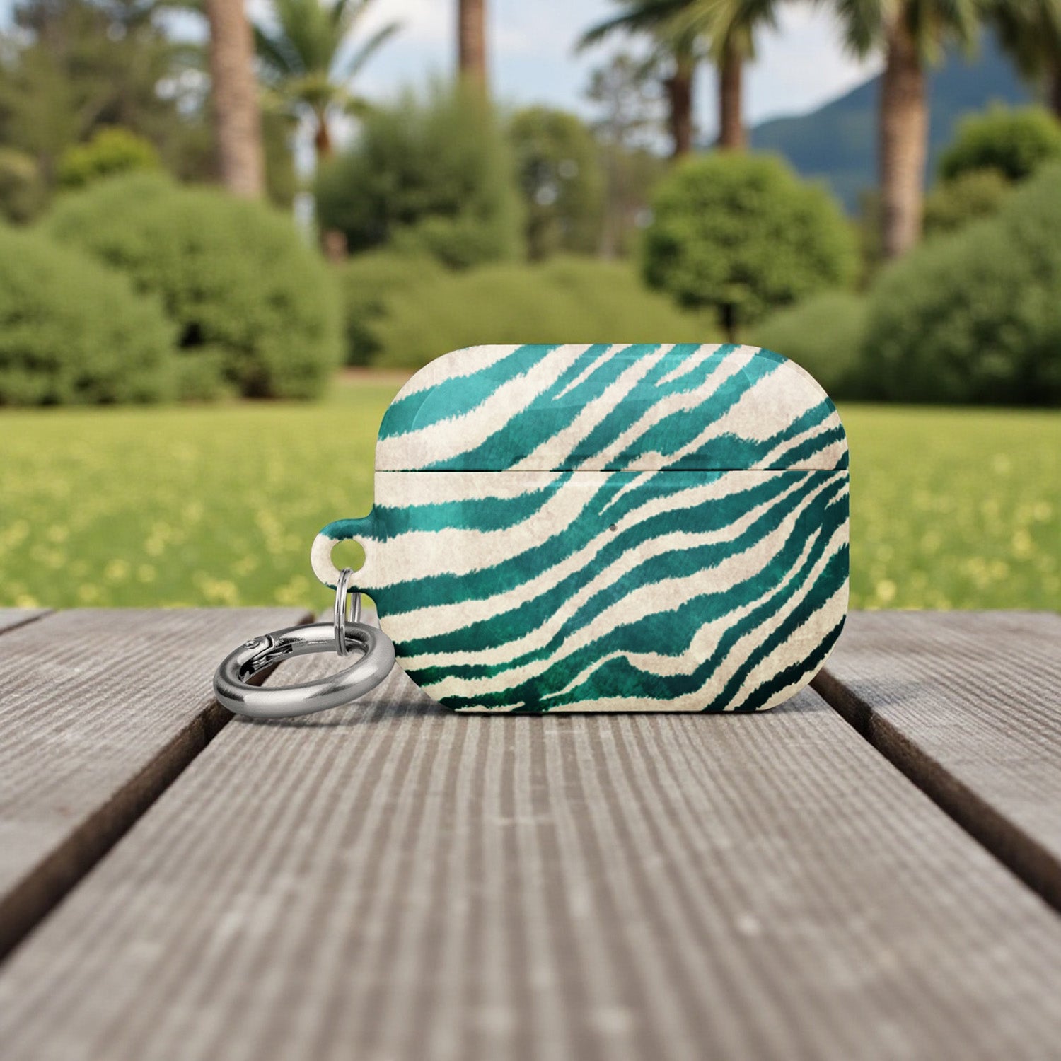 Green and white striped pouch with a keychain on a wooden surface with a blurred natural background