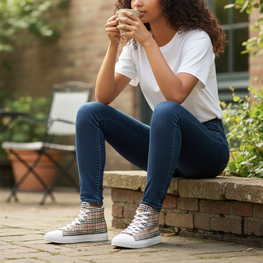 Woman sitting outdoors holding a mug, wearing plaid sneakers.
