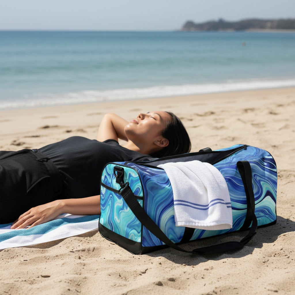 Person lying on a beach with a blue and black duffel bag and towel nearby