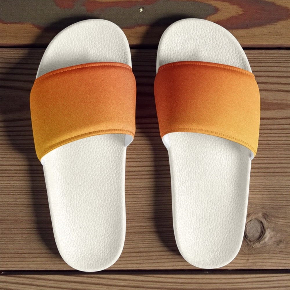Pair of white slides with orange bands on a wooden surface