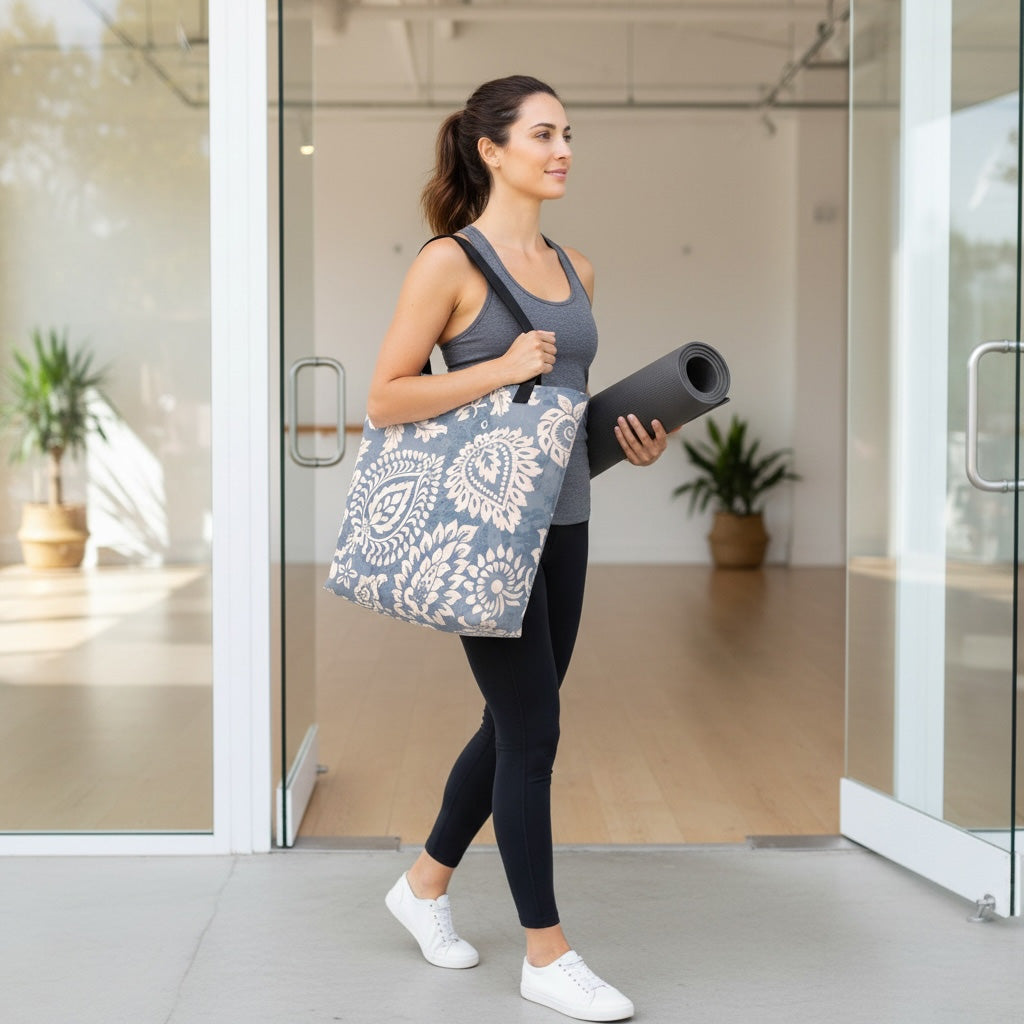 Woman holding a yoga mat and Yogi patterned tote bag exiting a building.