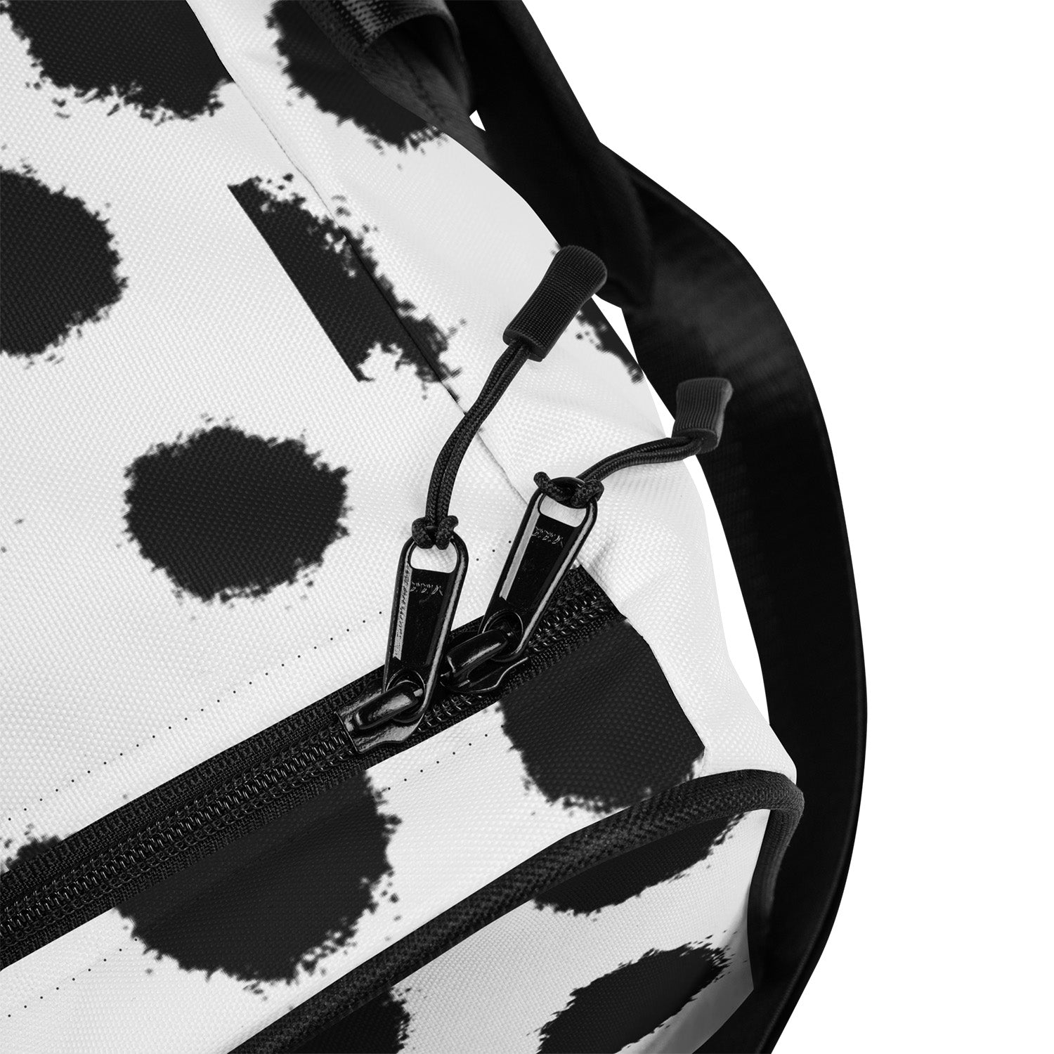 Close-up of a black and white patterned bag with a zipper and strap.