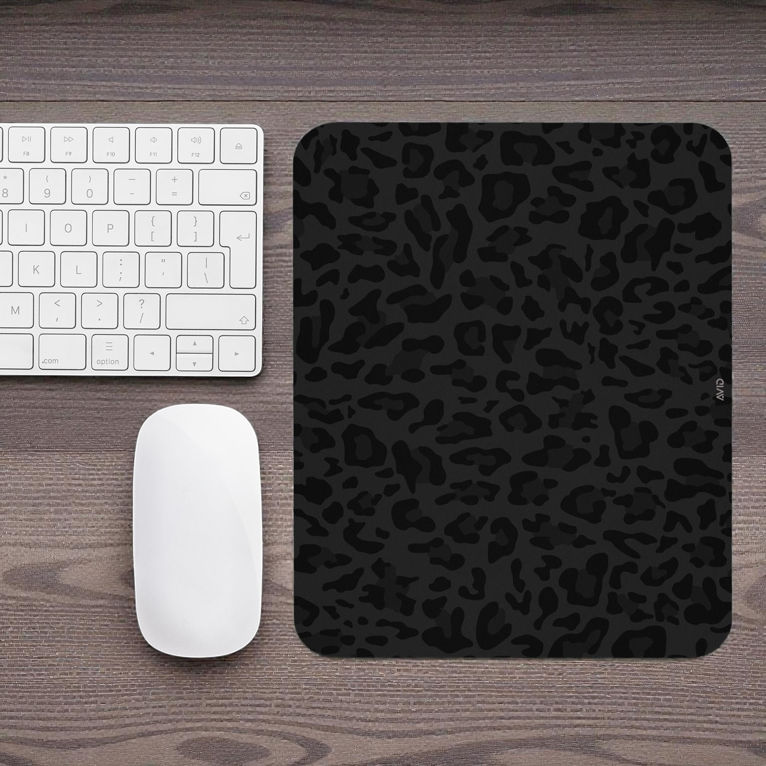 Black leopard print mouse pad on a wooden desk with a keyboard and mouse.