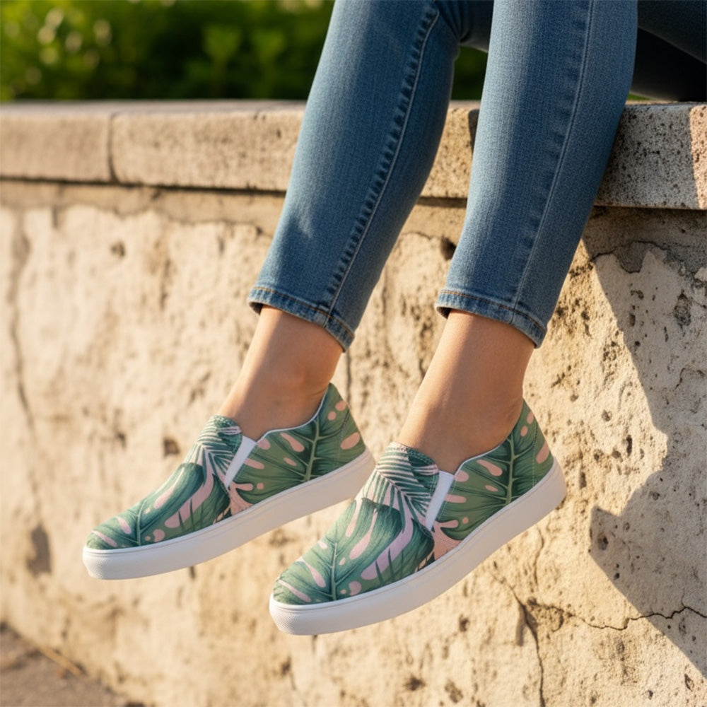 Green patterned sneakers worn with blue jeans against a stone wall.